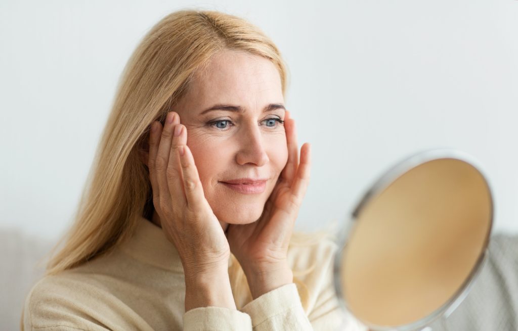 mujer de mediana edad mirándose al espejo satisfecha