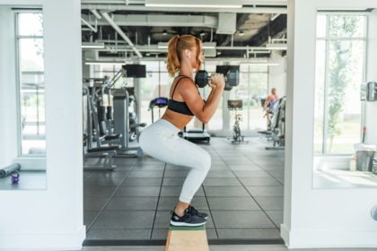 mujer en gimnasio haciendo entrenamiento de fuerza, sentadillas con mancuerna